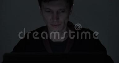 <strong>深夜</strong>在黑暗房间里用笔记本电脑工作的男人的肖像
